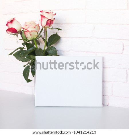 Mockup poster frame. White blank canvas and roses. Pink brick wall on background.