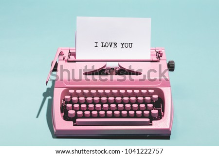 Pink vintage typewriter with a white sheet of paper and "I love you" written on it. Love concept.