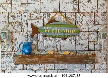 marine still life on stone background, fish with the word "welcome", seashells amd jug 