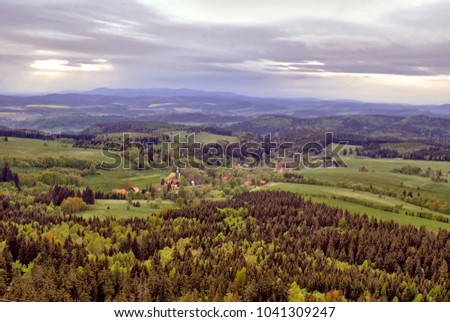 Aerial view from the mountains on the village that lays in the valley. Beautiful little town or country as seen from above. Rural scenery. Countryside, nature and architecture on one picture. 