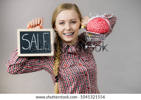 Happy woman holding shopping cart with brain inside and sale sign. Clever, responsible buying concept.