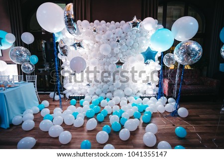 Photo-wall of white balloons and blue and silver balloons hanging before it in a dark dining hall