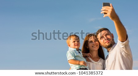 Happy Family are selfie with mobile phone and hug on the beach While relaxing on weekends with blur sea background in travel and holiday concept