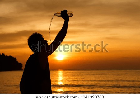 Men drinking water after exercise, with a yellow sky background in sunset by the sea.Silhouette picture