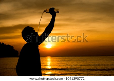 Men drinking water after exercise, with a yellow sky background in sunset by the sea.Silhouette picture