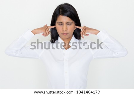 Closeup portrait of annoyed beautiful dark-haired woman stopping ears with fingers with her eyes closed. Irritation concept. Isolated front view on white background.