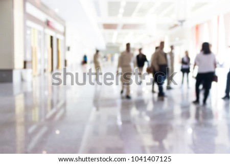 Blur image of company employees walk in the large hall.