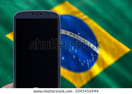 Holding smartphone with brazilian flag on the background