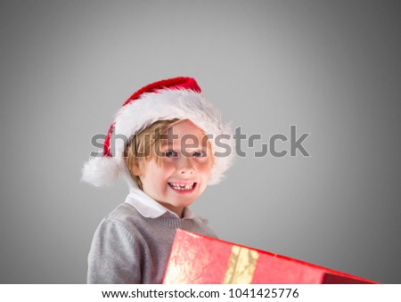 Digital composite of Boy against grey background with gift and Santa Christmas hat
