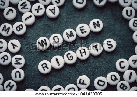 Words WOMEN RIGHTS made from small white letters on black stone background  