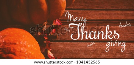 Happy thanksgiving day message against pumpkins and petals on wooden table
