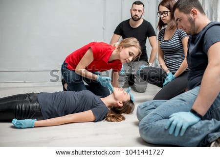 Young woman instructor showing how to lay down a woman during the first medical aid training indoors Royalty-Free Stock Photo #1041441727