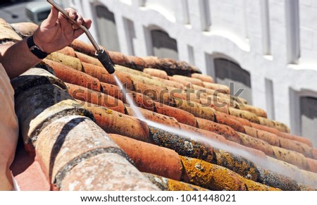 Closeup cleaning the traditional tiles roof with high pressure water jet