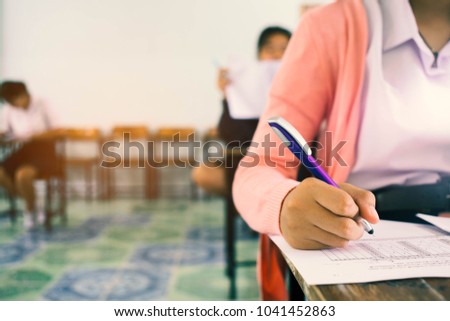 Students writing and reading exam answer sheets exercises in classroom of school with stress. Royalty-Free Stock Photo #1041452863