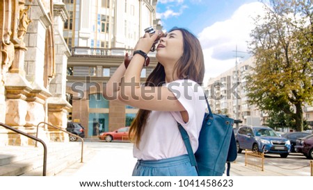 Image of beautiful tourist girl making photos of old cathedral