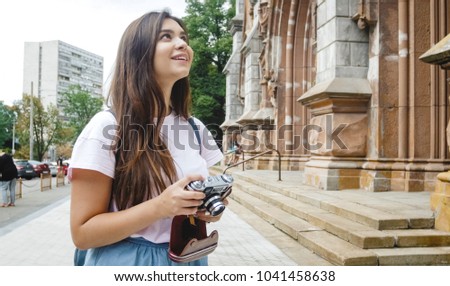 Smiling brunette tourist girl looking at old cathedral