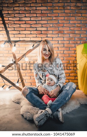 mother with her child on the background of a star with bulbs and a brick wall on the floor in the room