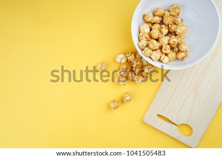 Movie or entertainment concept. Popcorns on a yellow background. Flat lay view.
