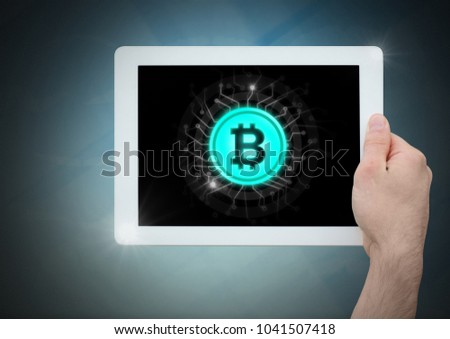 Digital composite of Bit coin icon and hand holding tablet