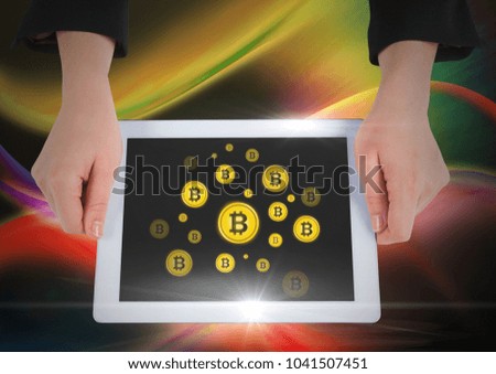 Digital composite of Bit coin icons and hands holding tablet