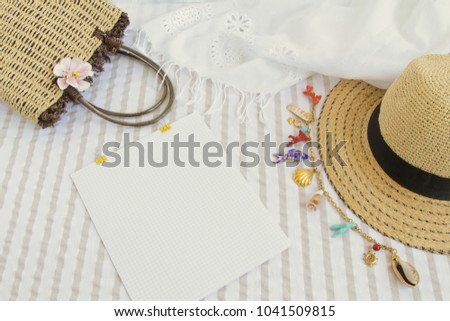 Preparing for a summer trip at sea. Straw hat with marine jewelry. Straw bag with flower. White embroidered scarf. Picture in light colors.Has a room for text. Clean sheet of paper, notepad for text.