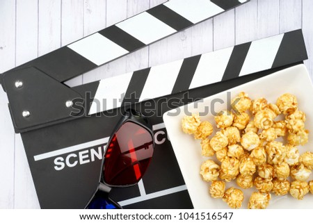 Popcorns, clapperboard and 3D glasses on a wooden textured background. 3D movie concept.