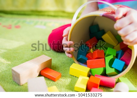 Small child playing with wooden blocks on green carpet - shallow depth of field