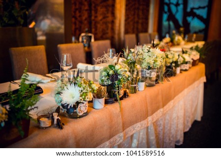 Wedding. Banquet. The chairs and table for guests, decorated with candles, served with cutlery and crockery and covered with a tablecloth.  Royalty-Free Stock Photo #1041589516