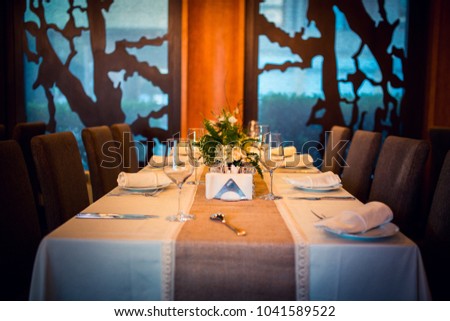 Wedding. Banquet. The chairs and table for guests, decorated with candles, served with cutlery and crockery and covered with a tablecloth.  Royalty-Free Stock Photo #1041589522