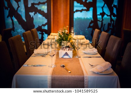 Wedding. Banquet. The chairs and table for guests, decorated with candles, served with cutlery and crockery and covered with a tablecloth.  Royalty-Free Stock Photo #1041589525