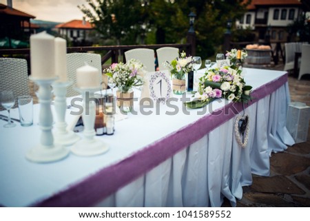 Wedding. Banquet. The chairs and table for guests, decorated with candles, served with cutlery and crockery and covered with a tablecloth.  Royalty-Free Stock Photo #1041589552