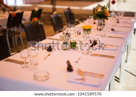 Wedding. Banquet. The chairs and table for guests, decorated with candles, served with cutlery and crockery and covered with a tablecloth.  Royalty-Free Stock Photo #1041589570