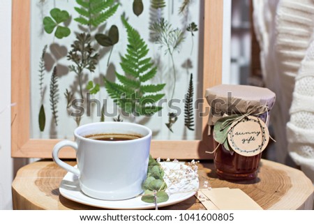 A cup of coffee and a picture with dried leaves, a herbarium. Element of decor.