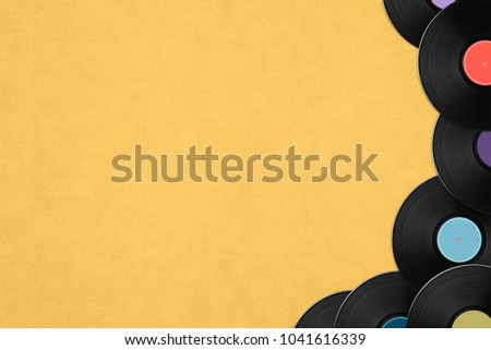Black vintage vinyl records with colorful label on yellow background. Top view on retro media plates, copy space.