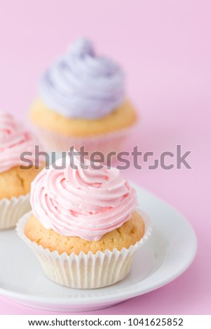 Cupcake decorated with pink and violet buttercream on pastel pink background. Sweet beautiful cake for wedding or birthday greeting card or invitation.