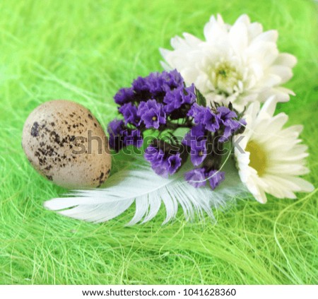 Easter still-life with flowers, eggs, feathers on a green sisal fiber with a sign
