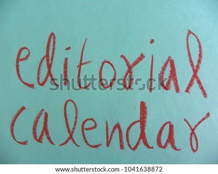 Text editorial calendar hand written by red oil pastel on blue color paper