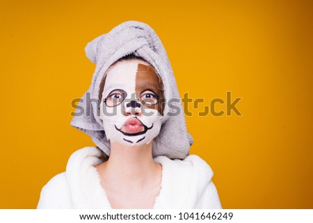 woman with a towel on her head apply a moisturizing mask on her face