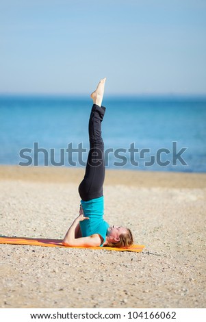 Young woman doing yoga on beach