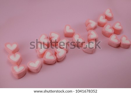 Pink heart marshmallows arrange in wording LOVE isolated on pink pastel background