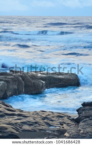 Moody ocean seascape with landscape of rocky beach during high tide