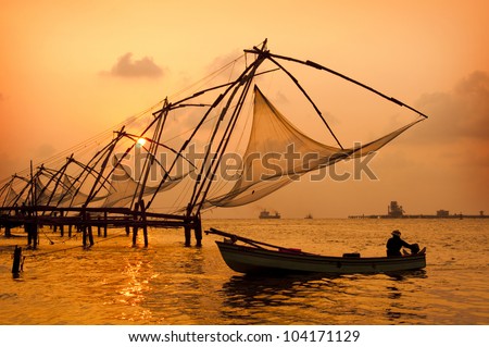 Sunset over Chinese Fishing nets and boat in Cochin (Kochi), Kerala, India. Royalty-Free Stock Photo #104171129