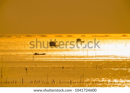 Silhouette of fisherman cottage and boatman in river on golden sunshine at morning time.