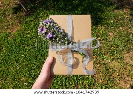 Hand holding Paper box with flowers and ribbon