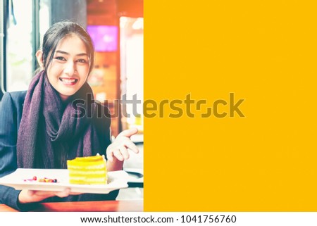 Attractive smiling young  asian woman eating cake and drinking coffee at a cafeteria. Cheerful designer having coffee break after work. Color filter effect with copyspace.