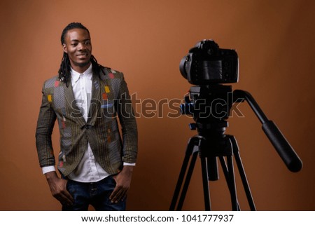 Studio shot of young handsome African businessman against brown background