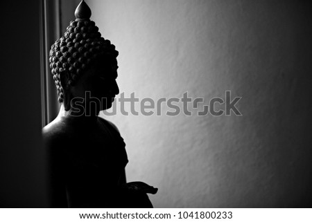 Buddha statue black and white picture. Light from behind.