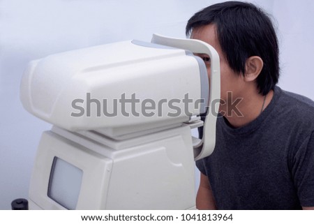 Young handsome asian man take eye exam with optical eye test machine