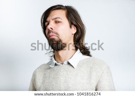 A handsome man does an unhappy look, with long hair, isolated studio photo