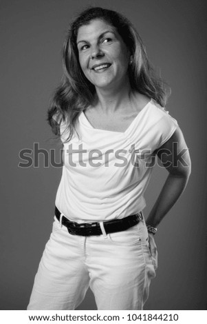 Studio shot of mature beautiful businesswoman against gray background in black and white